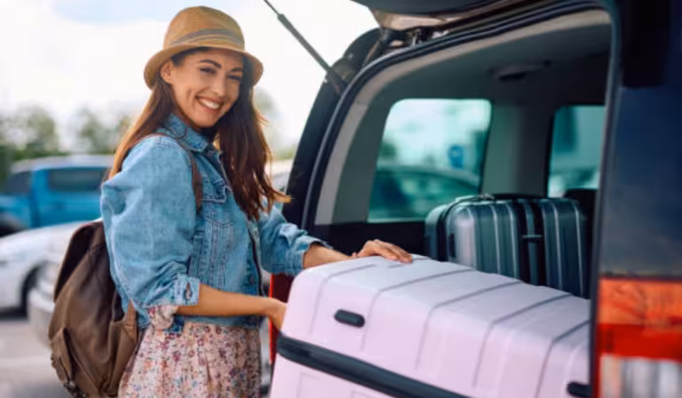 Woman putting suitcase into parked car